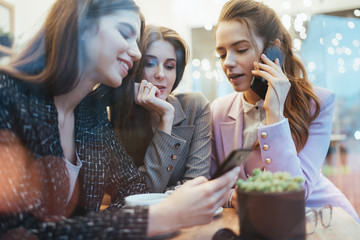 Three young attractive female entrepreneurs having meeting in cafe