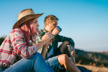 Couple of young attractive backpackers having rest after achieving mountaing top