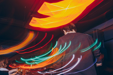 DJ mixer in a nightclub with moving motion abstract continuous lines glowing colored lights from controllers and buttons in the nightclub. Party music teen rave style long exposure 