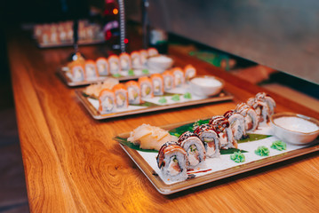 Close-up Set philadelphia eel smoked philadelphia Red Green dragon California ,Ebi Roll Rainbow Set rolls assorti ginger seaweed in night dining restaurant. Delicious Sushi rolls served in a bar.