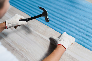 Close up hands of man installing new laminated wooden floor. Laminate flooring home renovation . Copyspace for text