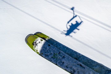 Skis above skiers shadows in chairlift above the white snow, during a Winter ski vacation in Les...