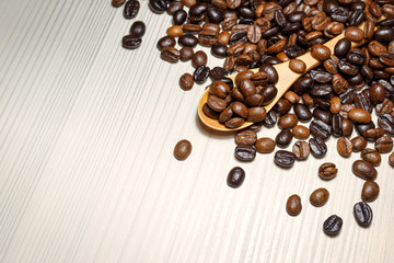 Coffee beans in wooden spoon on a light table