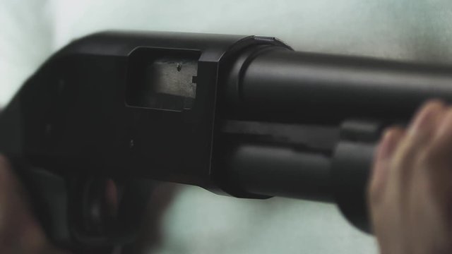 Man pumps a shotgun in slow motion as a spent shell pops out of the gun