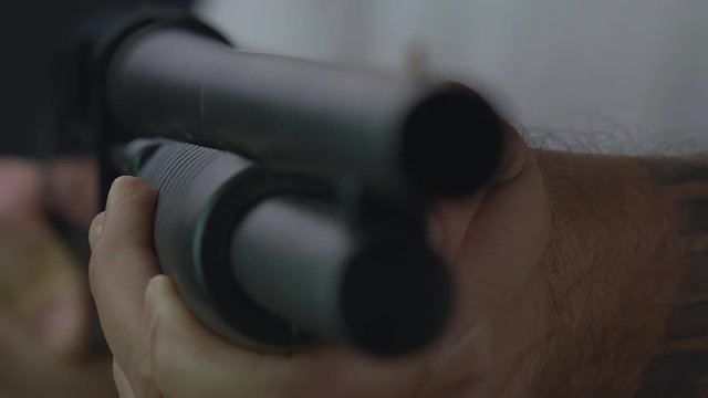 Man pumps a shot gun. Close up, shallow depth of field