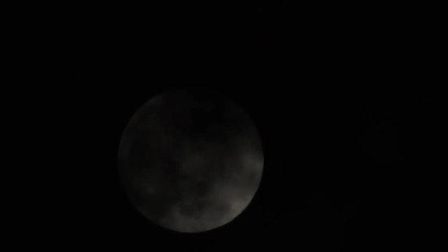 Full moon in night sky. Clouds float along the moon