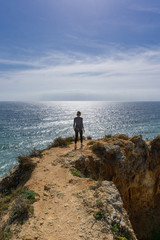 Fototapeta na wymiar Woman hikes ocean ridge to horizon in Portugal