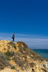 Female hiker looking out over ocean from ridge in Portugal