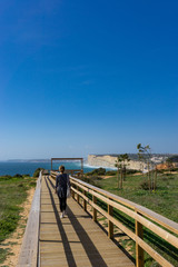 Hipster girl walking ocean cliff pathway in Portugal