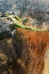 Male hiker looks down cliff face in Ponta da Piedade, Portugal