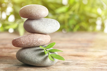 Spa stones and bamboo leaves on table against blurred background. Space for text