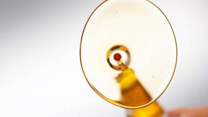 BOTTOM UP: Golden extra virgin olive oil is being poured onto a glassy surface.