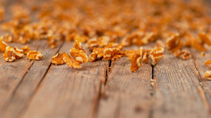 MACRO, DOF: Countless walnut kernels roll down the rustic wooden kitchen table.