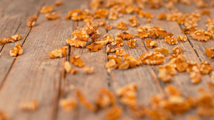 MACRO, DOF: Delicious organic walnut kernels roll down the wooden table.