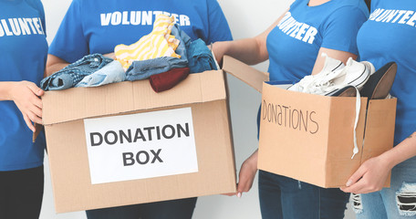 Team of volunteers with donation boxes on light background