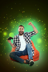 Naklejka premium Emotional man playing video games on color background