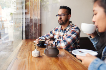 Two friends drinking coffee and tea together in a cafe