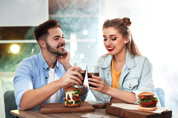 Happy young couple having lunch in burger restaurant