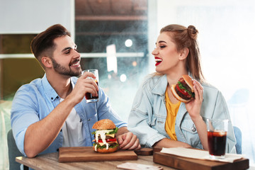 Happy young couple having lunch in burger restaurant