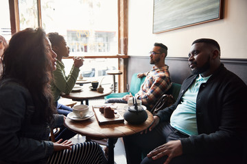 Diverse friends talking together over coffee in a cafe