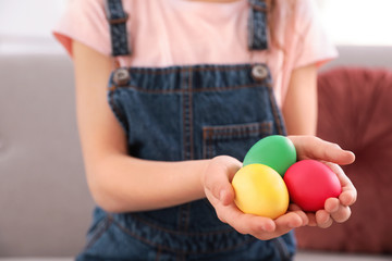 Fototapeta na wymiar Little girl holding Easter eggs indoors, closeup. Space for text