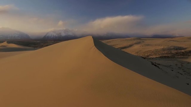 Unique Desert Sands Chara Yellow top dunes Siberia tundra picturesque landscape. Trans-Baikal Russia. Udokan mountains. Natural monument. Sunset Winter blue sky clouds. Aerial Low drift  horizon