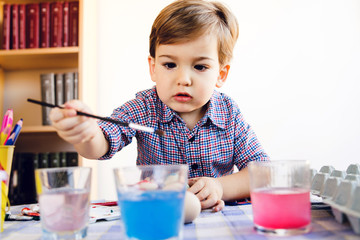 Little Boy Painting water color Easter Eggs At Home