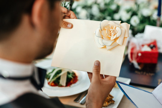 Close up of groom reading greeting card after wedding ceremony/.