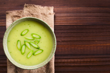 Cream of green asparagus soup in bowl, garnished with sliced asparagus on top, photographed...