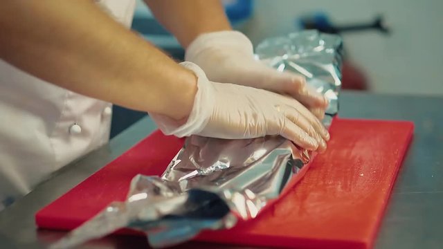 cook wraps the pickled meat in foil for subsequent baking in the oven.