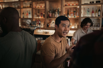 Young man talking with friends in a busy bar