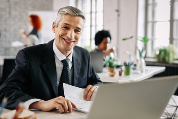 Fototapeta premium Happy businessman analyzing business reports in the office.