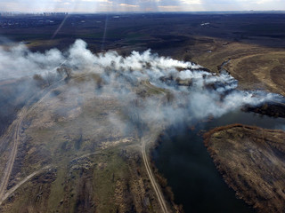 The smoke from the burning of dry grass (drone image).Local residents set fire to the grass specifically. Small animals are bending. Local features and habits. Near Kiev,Ukraine