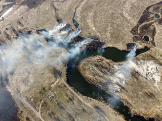 The smoke from the burning of dry grass (drone image).Local residents set fire to the grass specifically. Small animals are bending. Local features and habits. Near Kiev,Ukraine