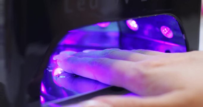 Professional hand care. View of wonderful female hand getting nail extension under the lamp for polymerization.