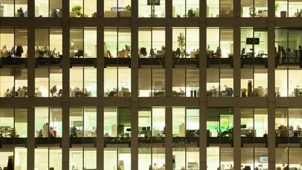 Timelapse of the exterior of an office block at night revealing the daily activity of office workers night themes of routines working late deadlines