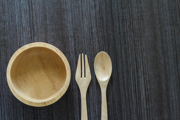 Wooden spoon and fork with wooden bowl on wooden table