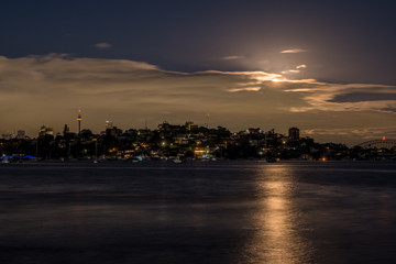 Night time moon behind clouds over Sydney Harbour