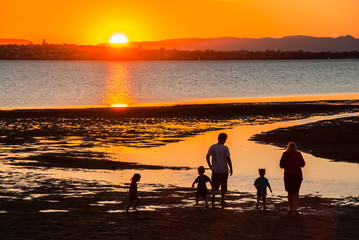 A family enjoys playing on the beach at sunset