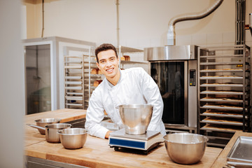 Dark-haired baker weighing some flour for future pastry