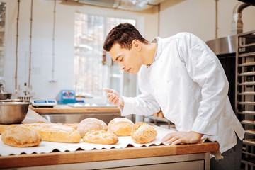 Fototapeta na wymiar Baker feeling satisfied while smelling just baked bread