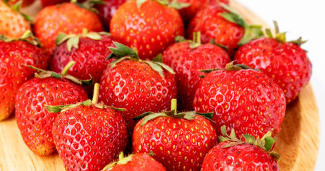 Strawberrys many with both ripe fruit and  not fruit ripe in wooden tray Strawberrys and wooden tray all laid are on a white background.