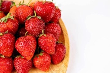 Strawberrys many with both ripe fruit and  not fruit ripe in wooden tray Strawberrys and wooden tray all laid are on a white background.