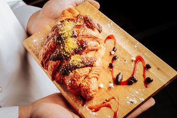 French croissant with chocolate topping near sugar powder