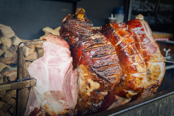 Large part of meat cooked on a rotate grill over open fire. Grilled   prepared outdoors. Smoked grilled Old Prague ham