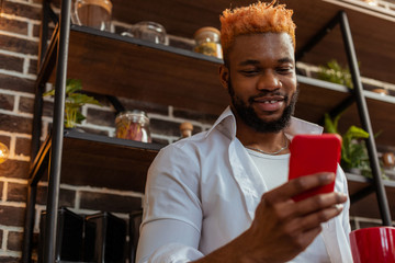 Positive African American man holding his smartphone