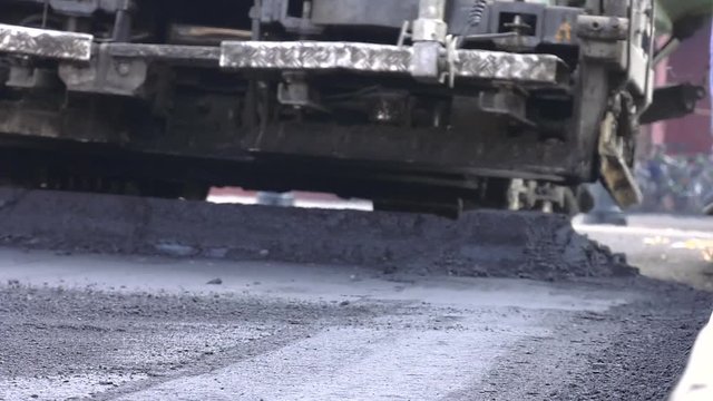 Laying the roadway. Worker shoveling shovels hot asphalt. Worker regulate tracked paver laying asphalt heated to temperatures above 160 &deg; pavement on a runway