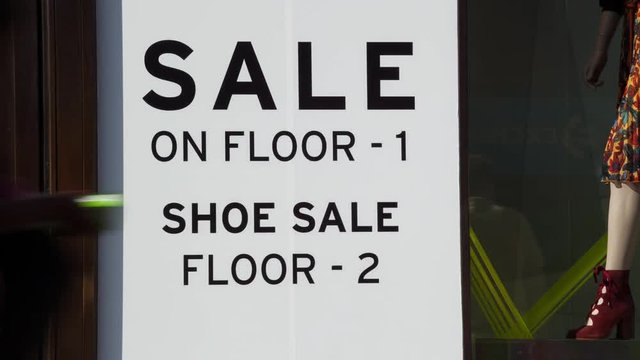 Timelapse of Pedestrians and shoppers walking past a sale sign in Oxford street London England themes of consumerism sign retail sale