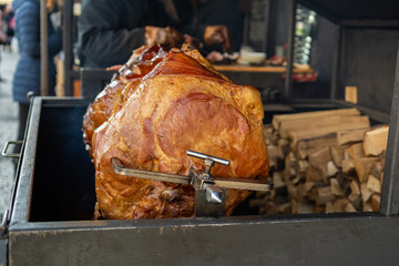 Large part of meat cooked on a rotate grill over open fire. Grilled   prepared outdoors. Smoked grilled Old Prague ham