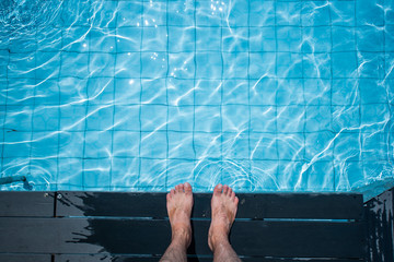 View From Above on Bare Male feet at Swimming Pool Side. Barefoot on swimming pool background